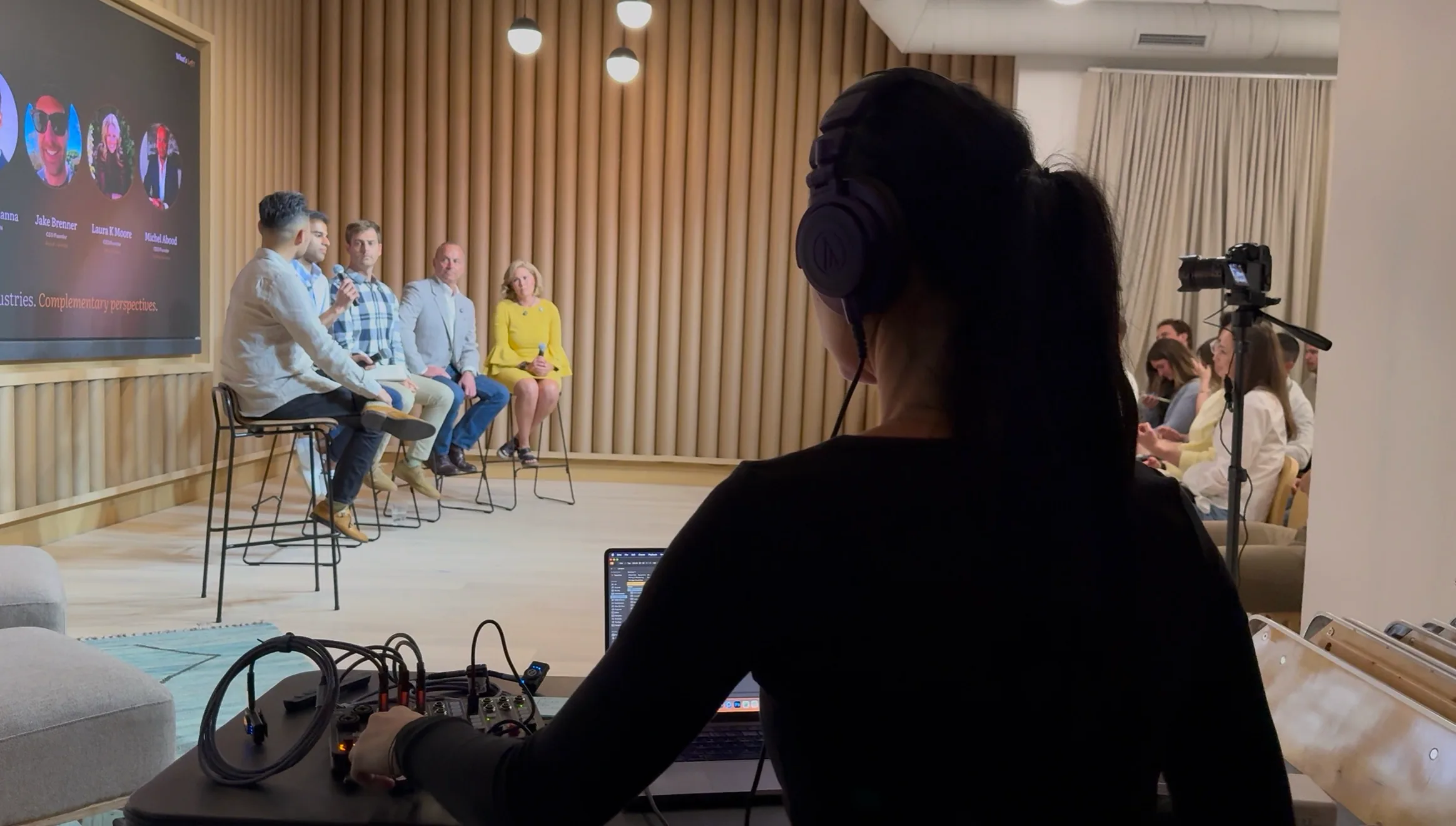 Audio engineer wearing headphones at a mixer while a panel discussion is recorded